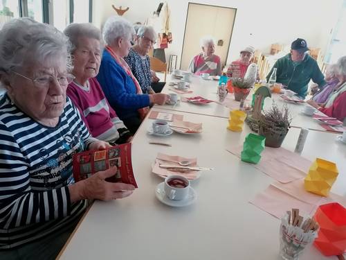 Gäste der Betreuungsgruppe am Tisch mit bunten, gebastelten Papierblumen.